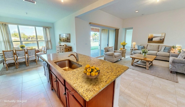 kitchen featuring light stone countertops, sink, and an island with sink