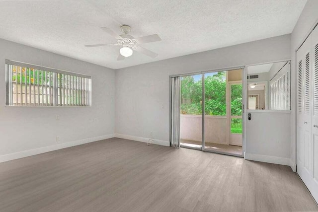 empty room featuring a textured ceiling, light hardwood / wood-style flooring, ceiling fan, and a healthy amount of sunlight