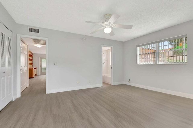 spare room with ceiling fan, light hardwood / wood-style floors, and a textured ceiling