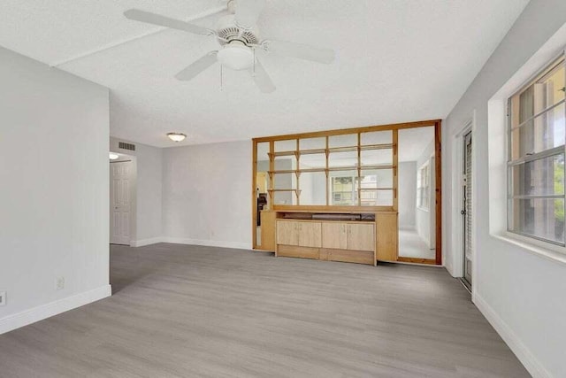 unfurnished living room with ceiling fan, wood-type flooring, and a textured ceiling