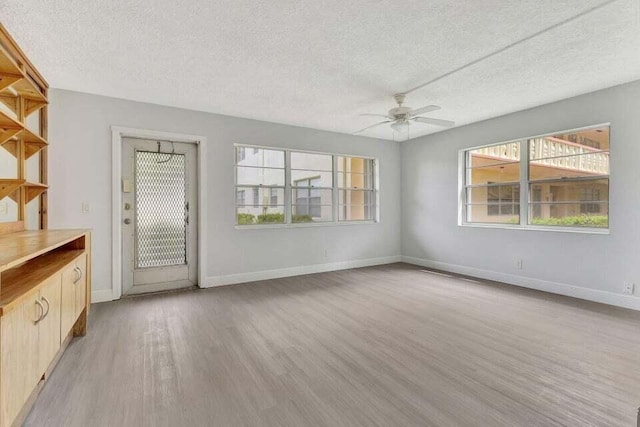 unfurnished living room with ceiling fan, light hardwood / wood-style floors, and a textured ceiling