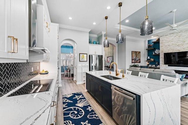 kitchen featuring stainless steel appliances, crown molding, sink, pendant lighting, and a center island with sink