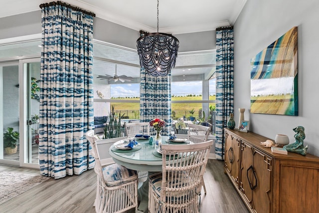 dining area with ceiling fan with notable chandelier, light hardwood / wood-style flooring, and crown molding