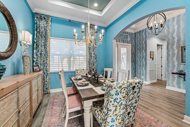 dining room featuring a raised ceiling, light hardwood / wood-style floors, a healthy amount of sunlight, and an inviting chandelier