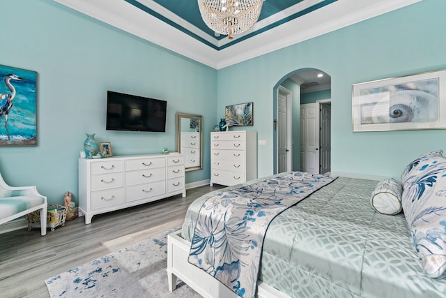 bedroom with a notable chandelier, ornamental molding, and light hardwood / wood-style flooring