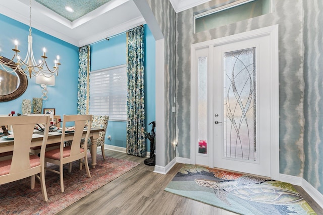 foyer entrance featuring an inviting chandelier, wood-type flooring, and ornamental molding