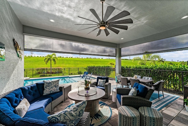 view of patio with an outdoor living space, ceiling fan, a fenced in pool, and a rural view