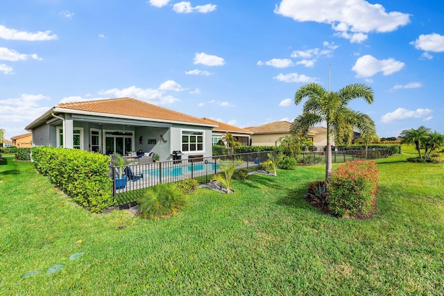 rear view of house featuring a lawn, a fenced in pool, and a patio