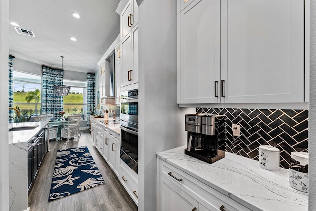 kitchen featuring pendant lighting, white cabinets, sink, dark hardwood / wood-style floors, and light stone countertops