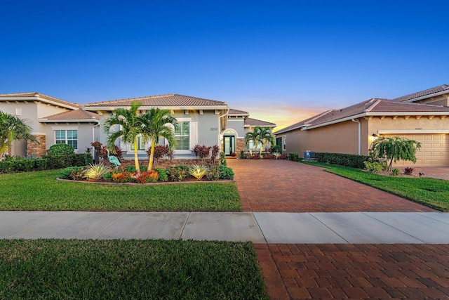 mediterranean / spanish-style home with a lawn, central AC, and a garage