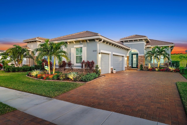 mediterranean / spanish-style home featuring a garage and a yard