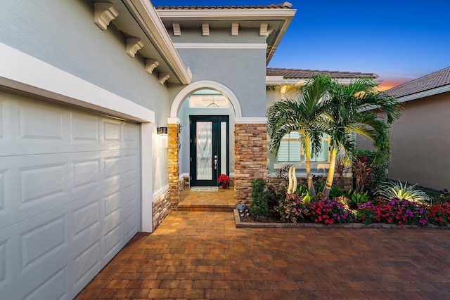 exterior entry at dusk featuring a garage