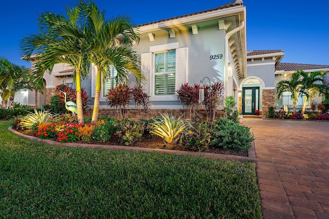 mediterranean / spanish-style home featuring french doors and a front lawn