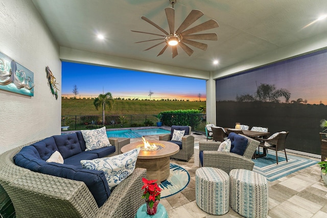 patio terrace at dusk featuring ceiling fan, a fenced in pool, and an outdoor fire pit