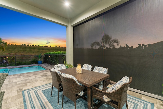 patio terrace at dusk featuring a fenced in pool