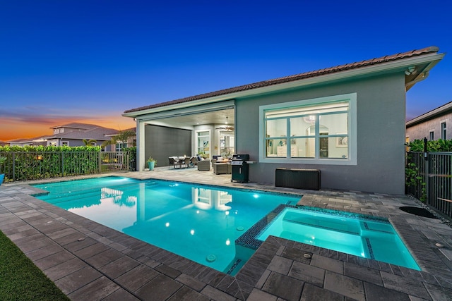 pool at dusk featuring a patio area, an in ground hot tub, ceiling fan, and an outdoor living space