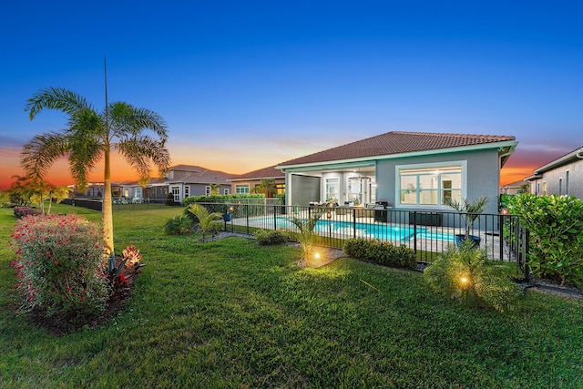 pool at dusk with a yard and a patio