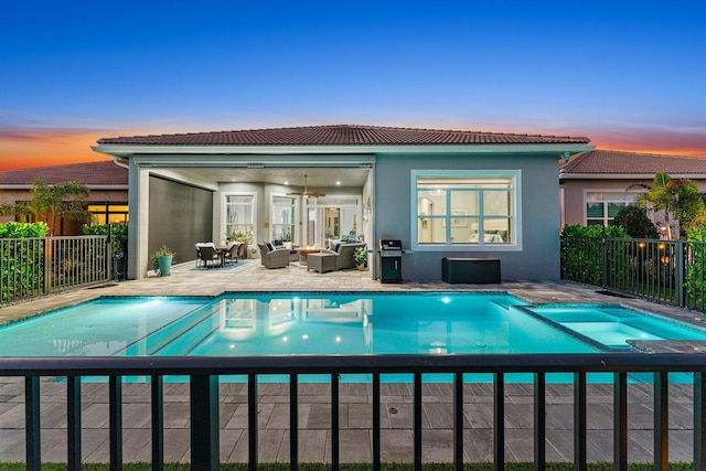 pool at dusk featuring outdoor lounge area, a patio, and grilling area