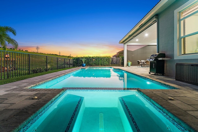 pool at dusk featuring a patio area, an in ground hot tub, and grilling area