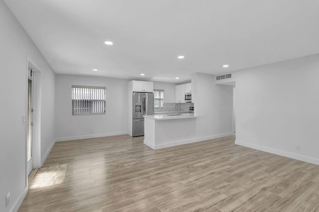 unfurnished living room featuring recessed lighting, visible vents, a sink, and light wood finished floors