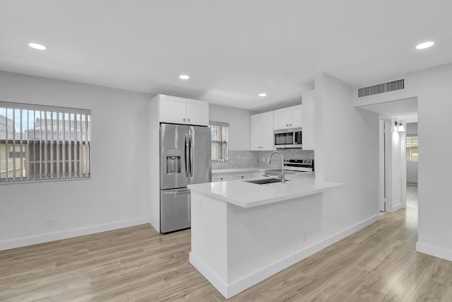 kitchen with decorative backsplash, stainless steel appliances, sink, light hardwood / wood-style flooring, and white cabinets