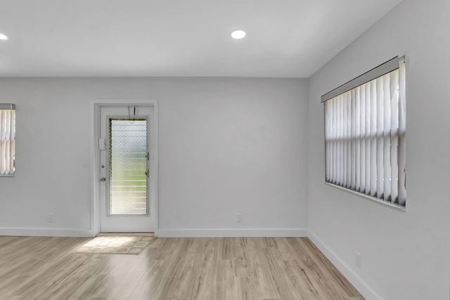 unfurnished room featuring light wood finished floors, a wealth of natural light, and baseboards