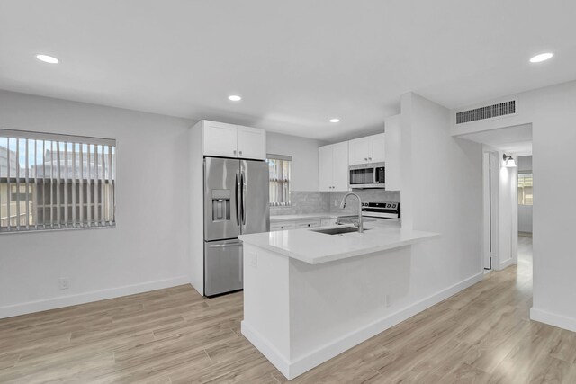 kitchen with stainless steel appliances, visible vents, backsplash, white cabinets, and a sink