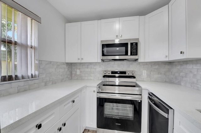 kitchen featuring white cabinets, backsplash, stainless steel appliances, and light stone countertops