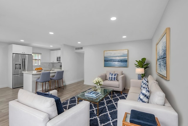 living room with light wood-type flooring, baseboards, visible vents, and recessed lighting