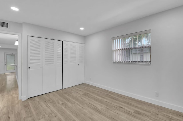 unfurnished bedroom with a closet and light wood-type flooring