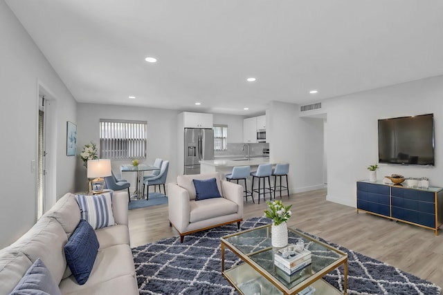 living room featuring baseboards, light wood-style flooring, visible vents, and recessed lighting