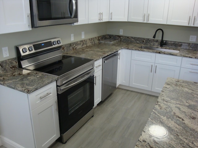 kitchen featuring white cabinets, dark stone countertops, sink, and appliances with stainless steel finishes