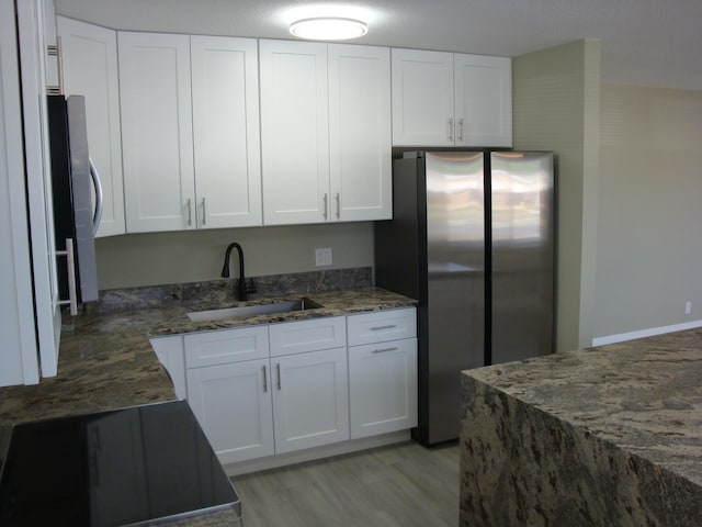 kitchen with stainless steel refrigerator, sink, refrigerator, dark stone counters, and white cabinets