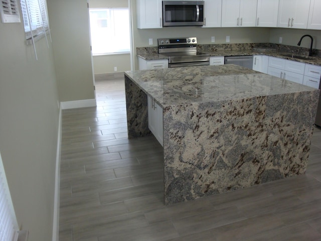 kitchen with stone counters, white cabinetry, sink, and appliances with stainless steel finishes