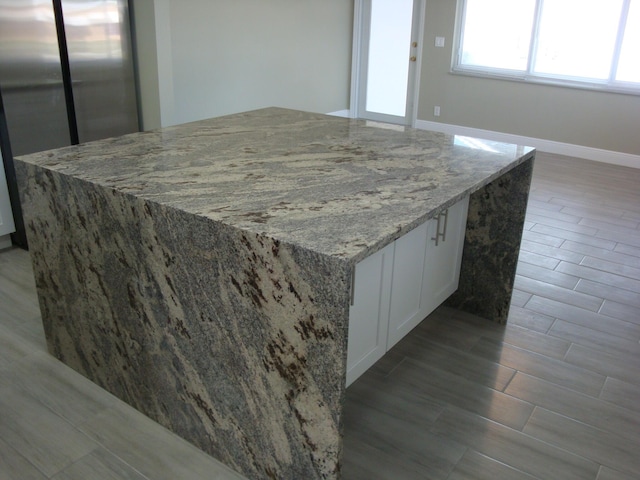 kitchen featuring light stone countertops, white cabinets, and stainless steel refrigerator