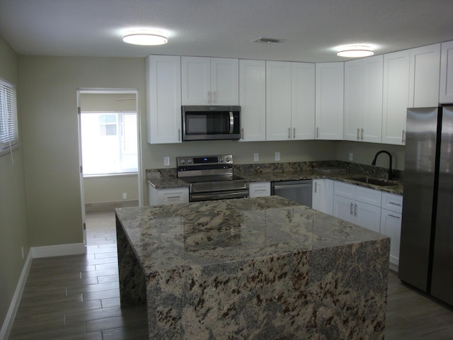 kitchen with dark stone counters, white cabinets, sink, a textured ceiling, and stainless steel appliances