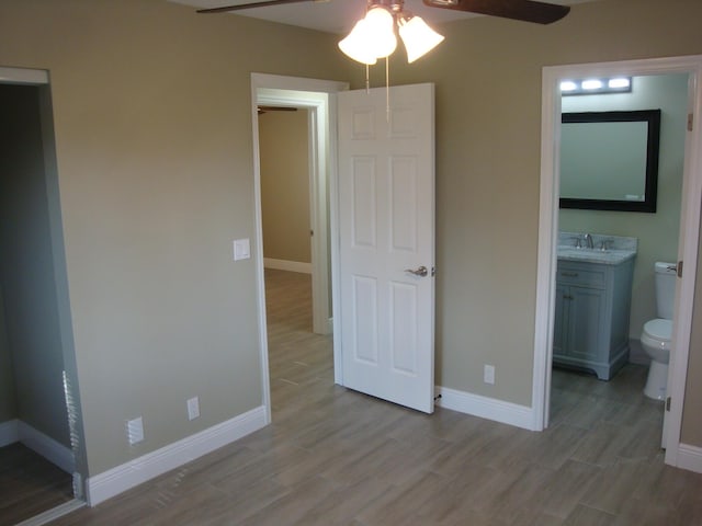 unfurnished bedroom with ensuite bathroom, ceiling fan, sink, and light hardwood / wood-style flooring