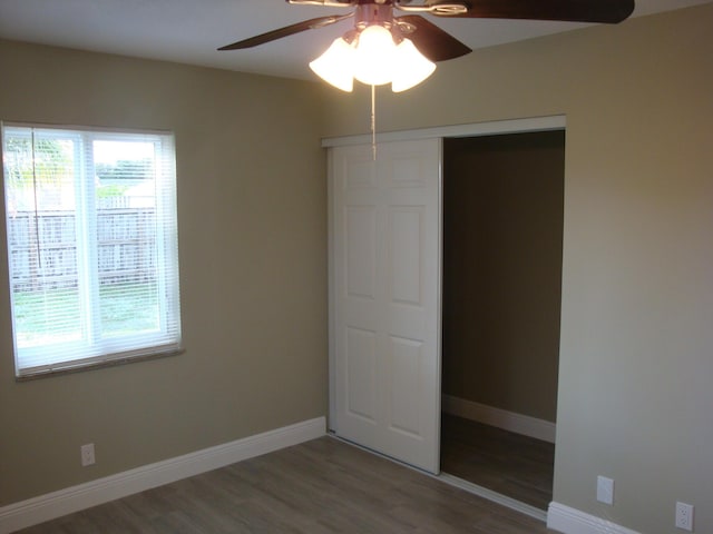 unfurnished bedroom featuring ceiling fan, wood-type flooring, and a closet