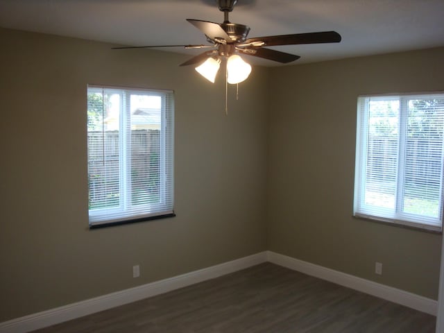 empty room with dark hardwood / wood-style floors, ceiling fan, and a healthy amount of sunlight