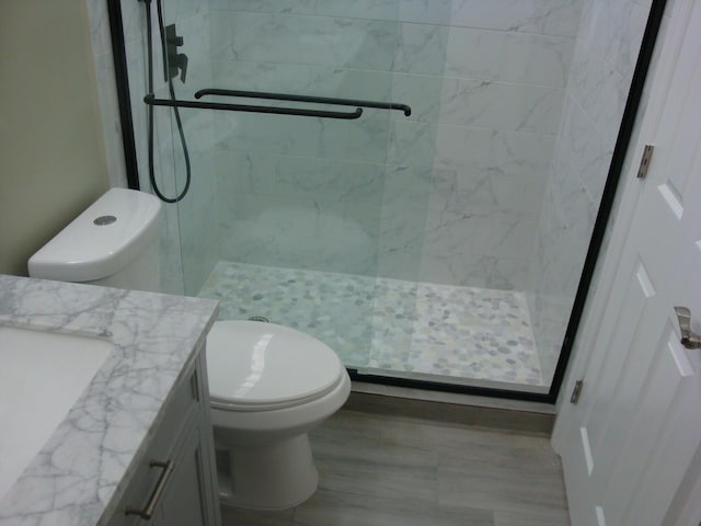 bathroom with tiled shower, vanity, and toilet