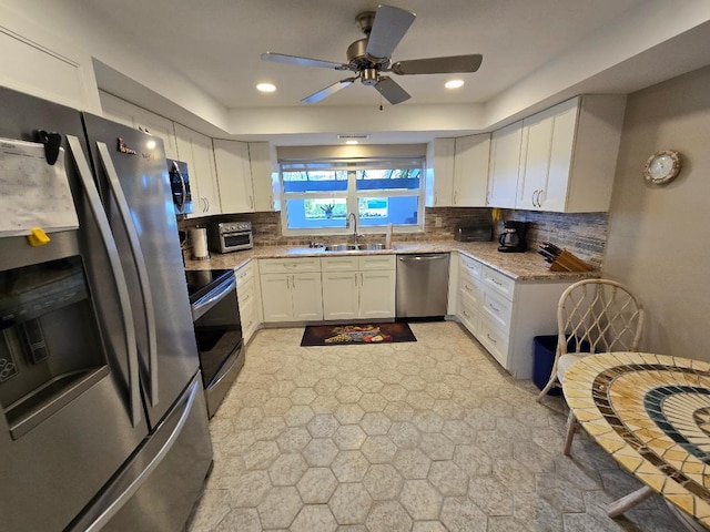 kitchen featuring white cabinets, sink, decorative backsplash, appliances with stainless steel finishes, and light stone counters