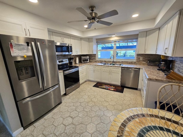 kitchen featuring white cabinets, sink, decorative backsplash, ceiling fan, and appliances with stainless steel finishes