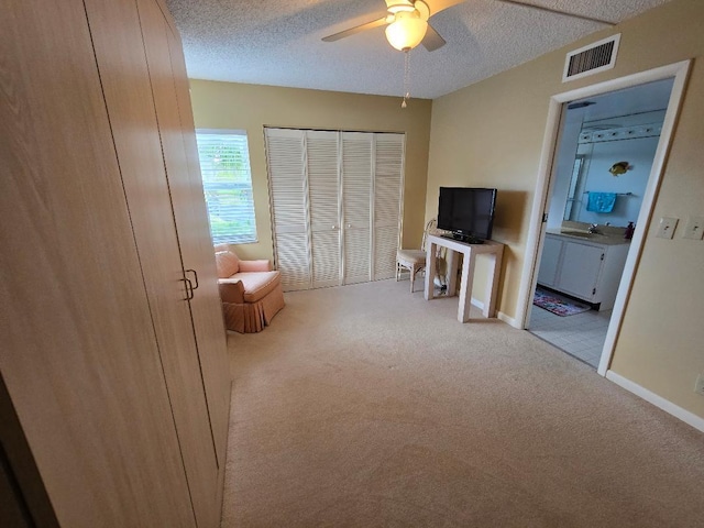 living area featuring a textured ceiling, ceiling fan, sink, and light carpet