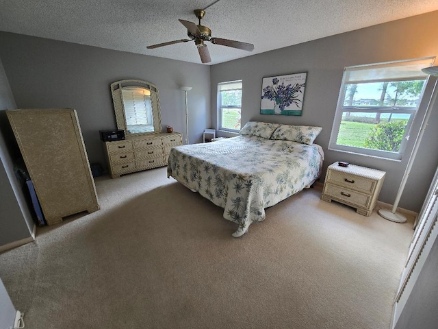 carpeted bedroom featuring ceiling fan and a textured ceiling