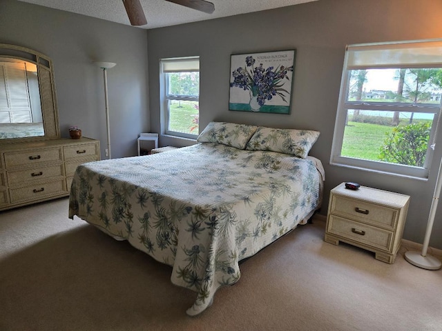 carpeted bedroom featuring ceiling fan and a textured ceiling