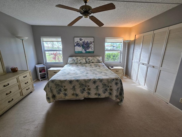 carpeted bedroom featuring ceiling fan, a closet, and a textured ceiling