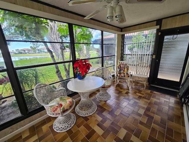 sunroom / solarium featuring a water view and ceiling fan