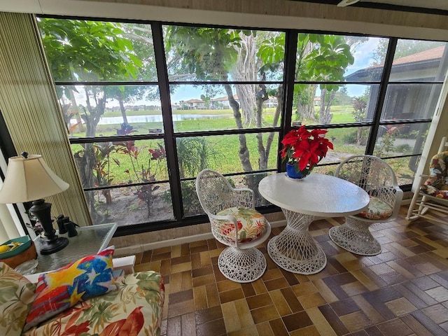 sunroom featuring a water view