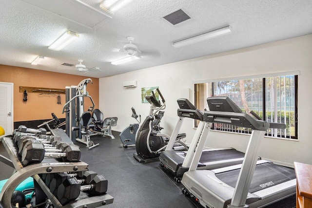 exercise room with a textured ceiling, an AC wall unit, and ceiling fan