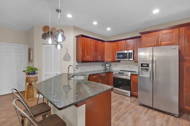1273 SW 48th Ter, Deerfield Beach, FL 33442 - kitchen with stainless steel appliances, a peninsula, a kitchen breakfast bar, decorative backsplash, and light wood-style flooring